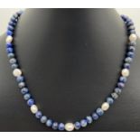 A 16" lapis lazuli and fresh water pearl beaded necklace with silver tone magnetic barrel clasp.