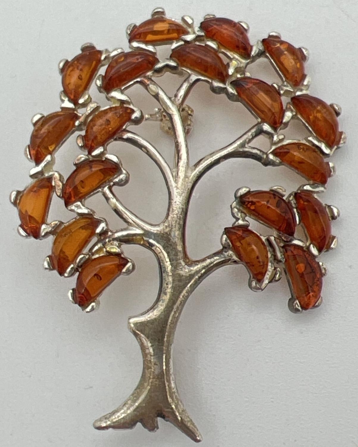 A 925 silver pendant/brooch in the shape of a tree, set with 19 small pieces of cognac amber.