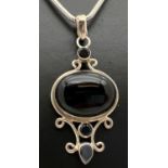 A decorative modern design silver drop pendant set with black onyx, on an 18" silver snake chain.