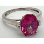 A 925nsilver and pink topaz solitaire dress ring. Oval cut stone set in a pierced work mount on high