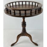 A vintage dark wood wine table with tripod feet, turned pedestal and galleried top. With brown