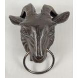 A cast iron wall hanging ornament modelled of a rams head with a ring. With fixing holes to reverse.