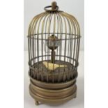 A brass ornamental wind up birdcage clock with winding mechanism to underside. Bird moves inside the