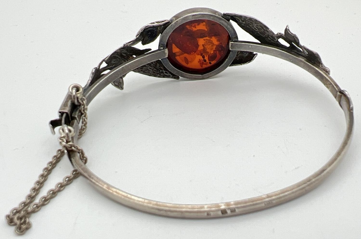 A silver bangle style bracelet set with a round cut piece of cognac amber with leaf design to both - Image 2 of 2