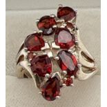 A silver statement dress ring set with teardrop, round, oval and heart shaped garnet stones. Swirl
