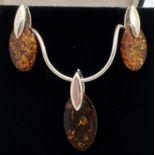 A modern design silver and amber necklace with matching drop earrings. Marquise cut piece of amber