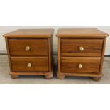 A pair of modern honey pine 2 drawer bedside cabinets with brass knob handles and bun feet. Each