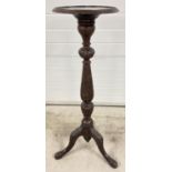 An antique mahogany torchere with carved floral detail to legs and pedestal. Bead rim detail to top.