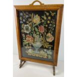 A vintage Art Deco oak framed needlepoint fire screen depicting a floral spray behind glass. Approx.