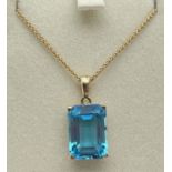 A modern 9ct gold large emerald cut blue topaz pendant, on an 18" foxtail gold chain with spring