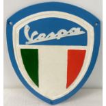 A Vespa shield shaped painted cast iron wall plaque. With fixing holes. Approx. 26cm x 21.5cm.