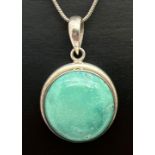 A silver circular pendant set with a cabochon of turquoise, on a 16" snake chain with lobster claw