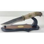 An ornamental survival style knife with display stand (a/f). Resin handle in the shape of a wolfs