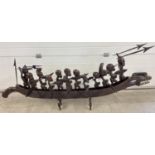 A large carved African sea dragon canoe with 12 carved African tribal figures each with a weapon. 10