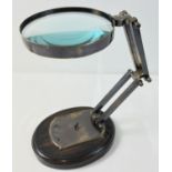 A large desktop magnifying glass with hinged folding stand with oval plaque for Watts & Sons Ltd, on