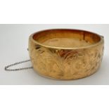 A vintage 9ct gold metal core hinged bangle with half floral engraved pattern, push clasp & safety