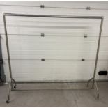 Heavy duty silver coloured metal clothes rail on wheels. Approx. 166cm tall and 184cm Long.