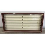 A modern slim line wall hanging display cabinet with glass shelves. Polished mahogany finish with