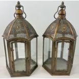 A large pair of Eastern style bronzed effect metal and glass panelled hexagonal lanterns with hinged