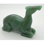 A carved jade figure of a deer, with ruby set eye (one missing). Approx. 6cm tall x 8cm long.