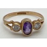 A 9ct gold, amethyst and cubic zirconia dress ring. Set with central bezel set oval amethyst flanked