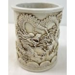 A Chinese white ceramic brush pot with dragon design shown in relief and shaped bottom rim.