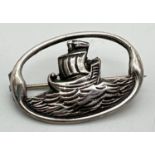 A vintage silver oval shaped brooch modelled as a Viking ship on the sea. Hallmarked Robert Allison,