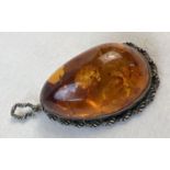 A large cognac amber pendant with a silver rope design mount and bale. Silver marks to bale. Pendant