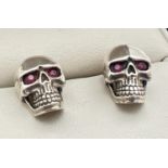 A pair of silver skull shaped stud earrings set with rubies. Reverse of earrings and butterfly backs