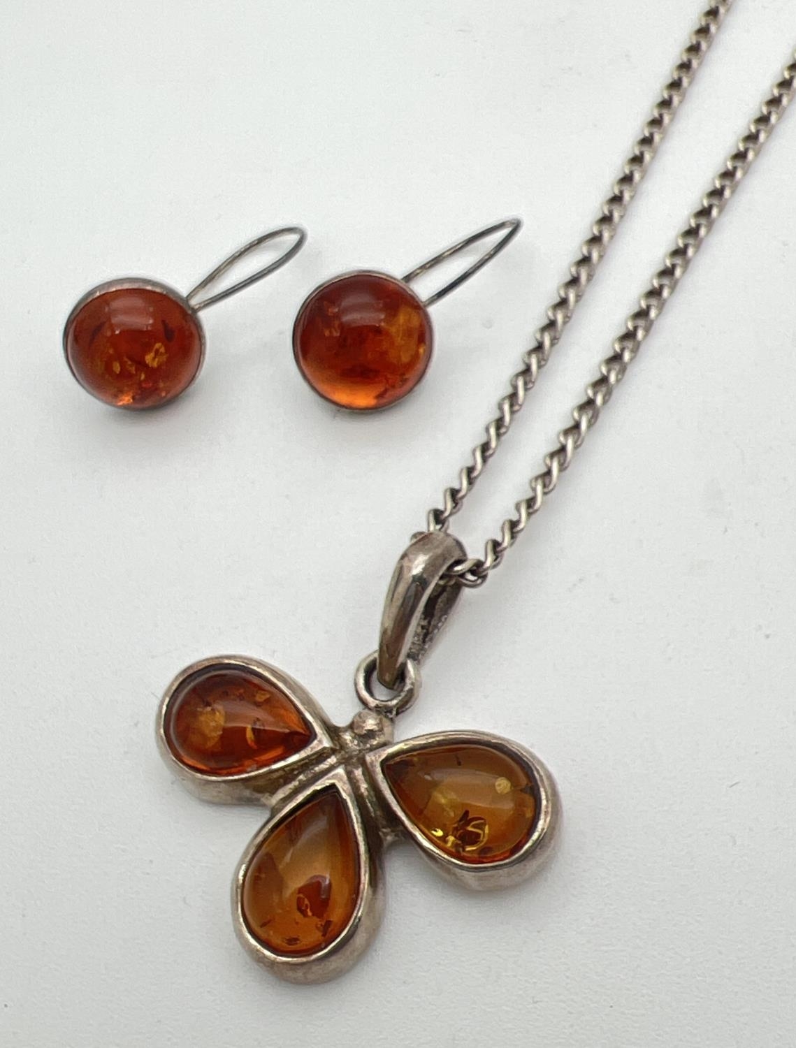 A flower design silver and amber pendant on a 20 inch curb chain with spring ring clasp. Together