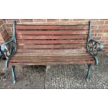 A wooden slatted garden bench with cast iron ends, painted green, with scroll detail. Needs