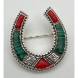 A silver horseshoe shaped pin back brooch set with alternate malachite and coral pieces. With