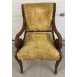 A Victorian wooden framed armchair with scroll detail to arms and carved legs. Velvet upholstered