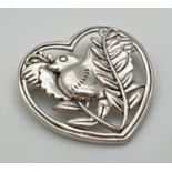 A sterling silver brooch in the shape of a heart featuring a bird with pierced design. Stamped to