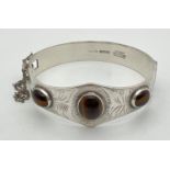 A vintage silver Excalibur bangle set with 3 tigers eye cabochons. Engraved detail to front, push