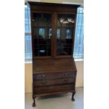 An early 20th century dark wood bureau bookcase raised on 4 ball & claw feet. 2 door glazed bookcase