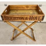 A modern wooden butlers tray table with metal banding and advertising for Brighton Pier. Folding