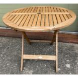 A circular shaped 'Royal Craft' teak folding garden table with umbrella hole and slatted top.