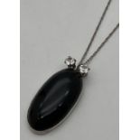 An oval shaped pendant set with black onyx, with 2 round cut clear stones to top. On an 18" fine