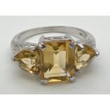 A silver and citrine 3 stone cocktail ring, set with square cut central stone flanked by 2 trilliant