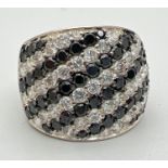 A silver multi-stone dress ring set with alternating rows of black & clear cubic zirconias.