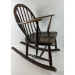 A mid century Ercol dark wood child's rocking chair with looped spindle design back. With blue