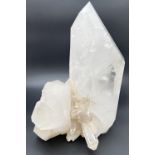 A large clear crystal quartz wand with multiple cluster detail. Natural white, black and orange