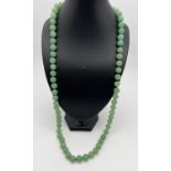 A 33" string of apple green jade beads, knotted between each bead. Beads approx. 1.2cm diameter.