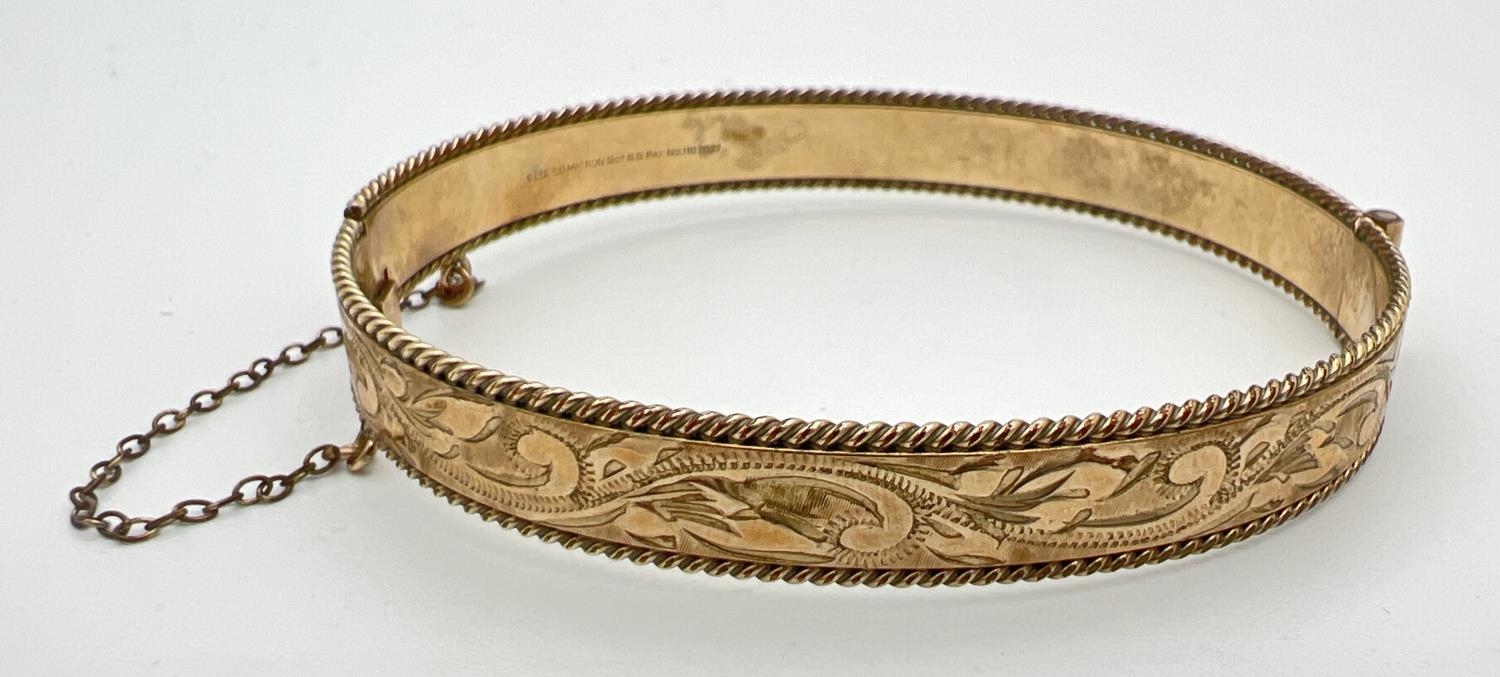 A vintage 9ct rolled gold bangle with floral engraving, push clasp and safety chain. Marks to inside