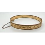 A vintage 9ct rolled gold bangle with floral engraving, push clasp and safety chain. Marks to inside