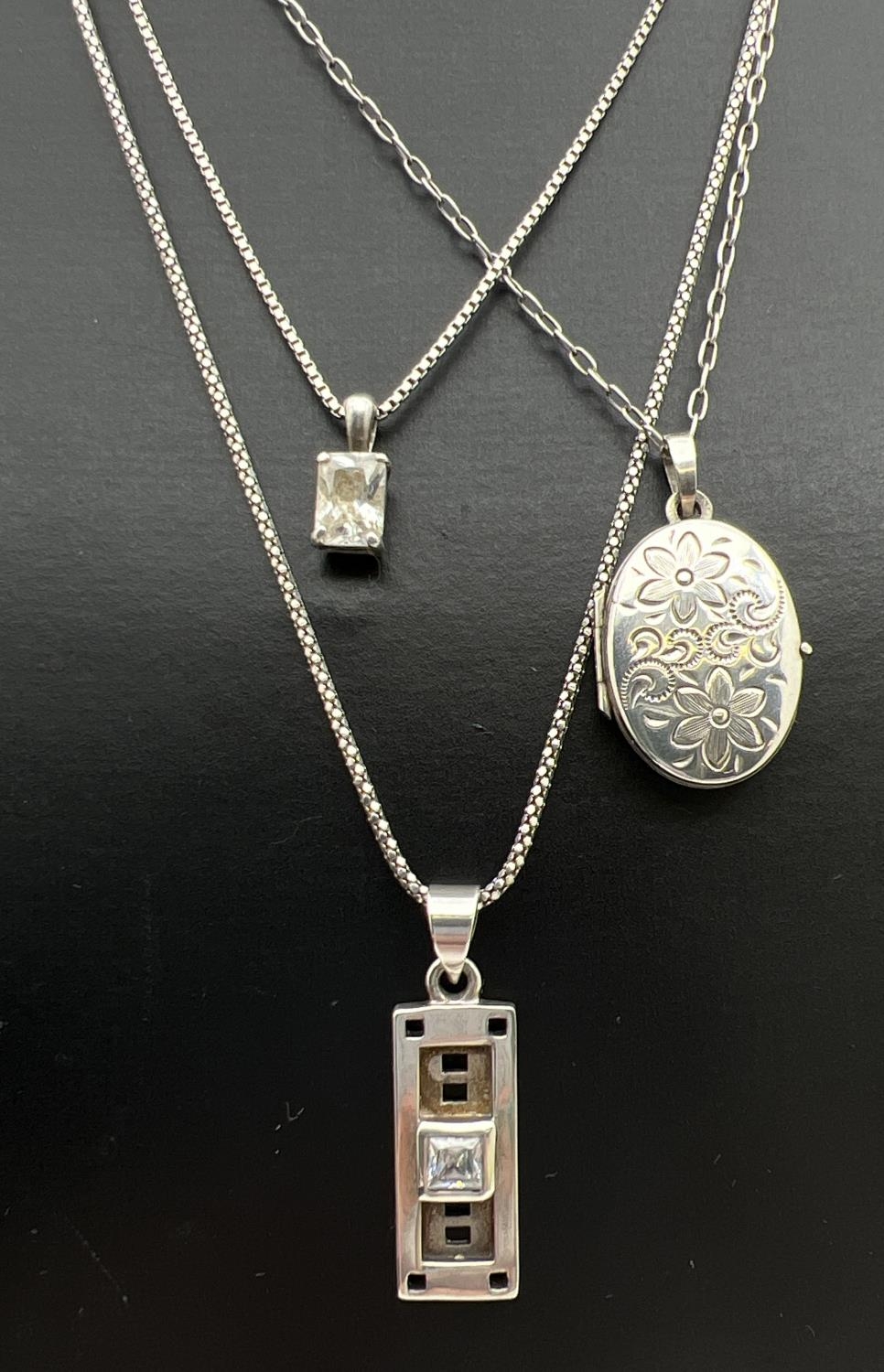 3 silver pendant necklaces. A square cut clear stone pendant on a 16" box chain; an oval shaped