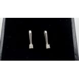 A pair of modern design 9ct white gold earrings each set with a 0.05ct diamond. Gold and diamond