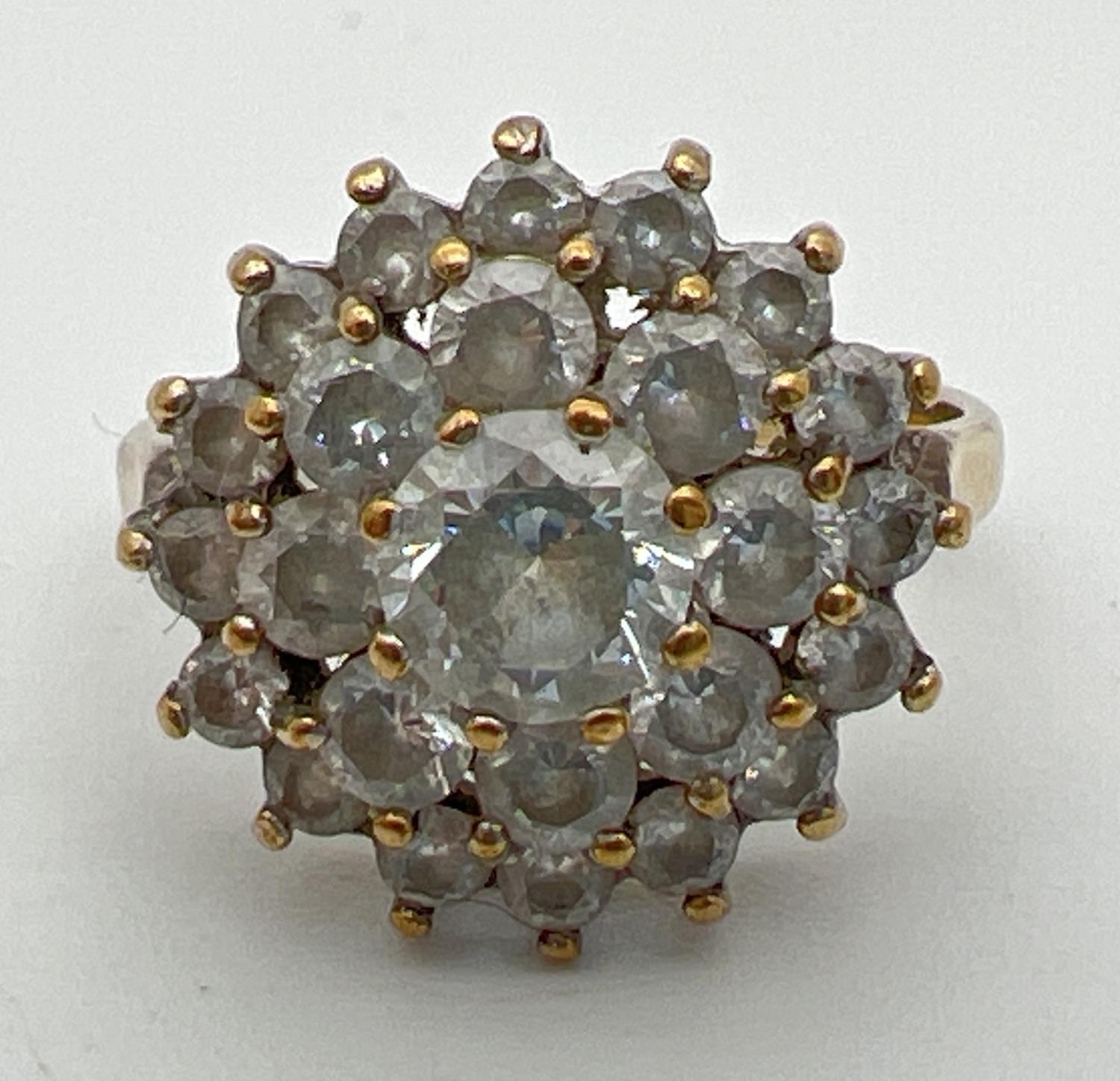 A 9ct gold and cubic zirconia large cluster ring. Central round cut stone surrounded by 2 rows of