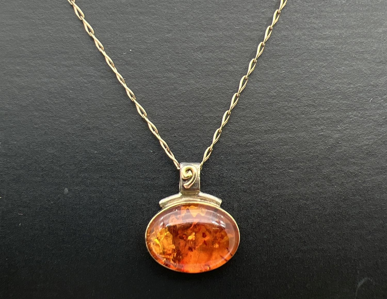 A silver and 18ct gold accent amber set oval pendant with spiral detail to bale on a 18ct gold 18